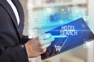 Genç kişi, HOTEL Arama yazısıyla online alışveriş uygulaması üzerinden alışveriş yapıyor