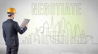 Elinde NEGOTIATE yazıtları, mühendisliği ve mimari konsepti olan sağlam şapkalı bir işadamı.