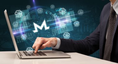 iş adamı borsada çalışıyor ve dizüstü bilgisayardan monero simgeleri çıkıyor