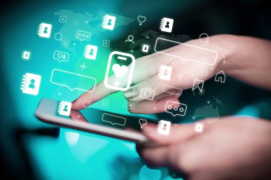İçinden kalp simgeleri çıkan akıllı telefonlu tablet kullanan bir elin yakın çekimi, sosyal medya kavramı