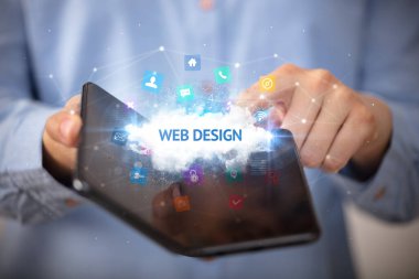 WeB DESIGN yazıtlı, teknoloji konseptli katlanabilir bir akıllı telefon tutan bir iş adamı