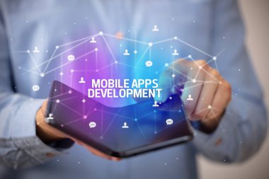 MOBILE APPS DEVELOPMENT yazıtları, yeni teknoloji konsepti ile katlanabilir bir akıllı telefon tutan iş adamı