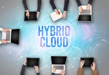HYBRID CLOUD insciption, web güvenlik kavramı olan bir dizüstü bilgisayarın önünde bir grup insan