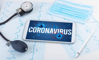 Beyaz yüzeyde CORONAVIRUS yazıtı, salgın konsepti içeren tablet pc ve doktor araçları