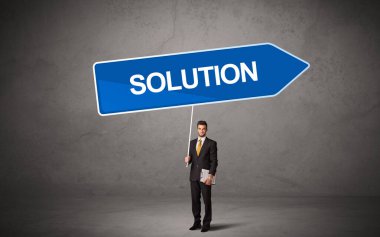 Genç iş adamı, günlük bekleme yolu tabelasında SOLUTION yazısıyla, yeni iş yönü kavramı