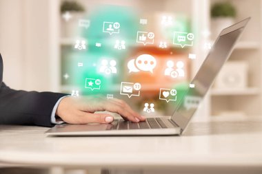 Mesajlaşma simgeleri ve sosyal medya konseptiyle dizüstü bilgisayarda sörf yapan genç kişi