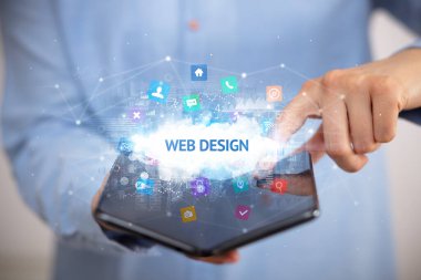 WeB DESIGN yazıtlı, teknoloji konseptli katlanabilir bir akıllı telefon tutan bir iş adamı