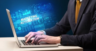 MARKETING AUTOMATION yazıtları, siber teknoloji kavramı ile birlikte dizüstü bilgisayarda çalışan bir işadamı