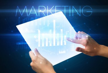 Üzerinde MARKETING yazıtları olan el ele tutuşan fütürist tablet, modern iş kavramı