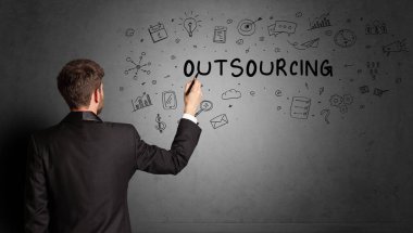 İş adamı, OutTSOURCING yazıtları ve iş stratejisi konseptiyle yaratıcı bir fikir çizimi yapıyor.