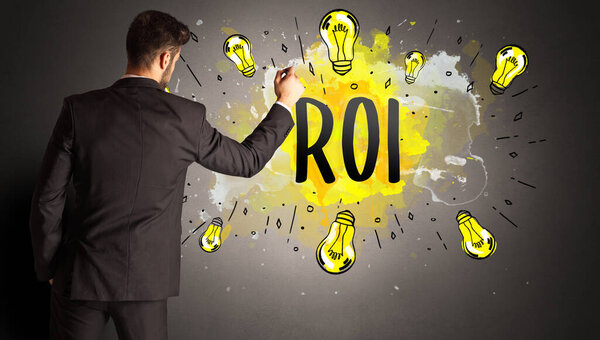 businessman drawing colorful light bulb with ROI abbreviation, new technology idea concept