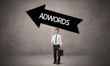 ADWORDS yazıtları, iş yönetimi konsepti ile günlük bekleme yolu tabelasında genç iş adamı