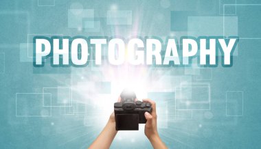 Fotografik yazı ve seyahat konseptiyle el ele tutuşan dijital kameranın yakın çekimi