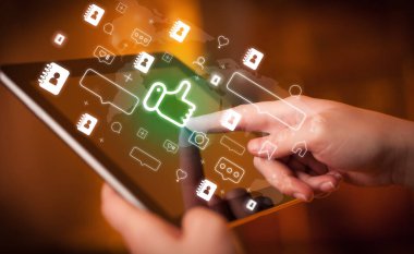 İçinden ikonlar çıkan tablet kullanan bir elin yakın plan resmi, sosyal medya kavramı