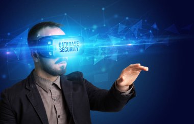 Businessman looking through Virtual Reality glasses with DATABASE SECURITY inscription, cyber security concept
