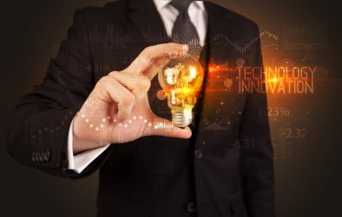 TEKNOLOJİ İHTİM, İş Teknolojisi kavramına sahip bir iş adamı elinde ampul tutuyor