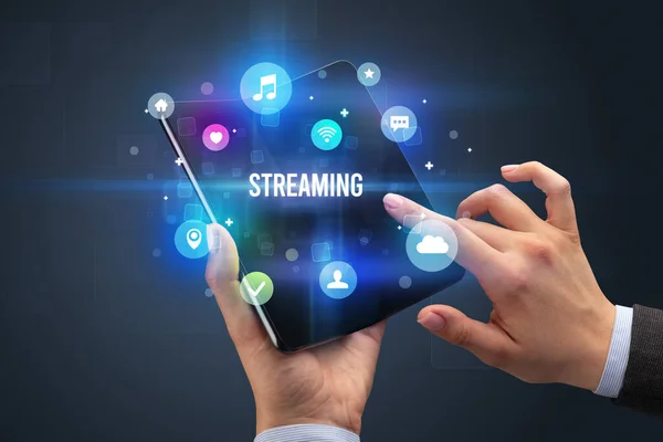 Adamı Elinde Katlanabilir Bir Akıllı Telefon Tutuyor Üzerinde Streaming Yazıtları — Stok fotoğraf