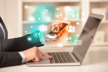 Akıllı telefon sohbet ikonları ve sosyal medya konseptiyle dizüstü bilgisayarda sörf yapan genç kişi