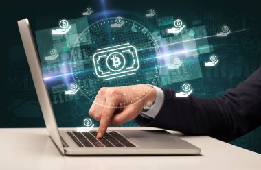 Borsada çalışan iş adamı dizüstü bilgisayardan çıkan bitcoin para simgeleriyle