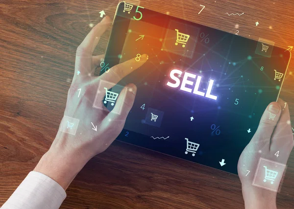 Close-up of a hand holding tablet with SELL inscription, online shopping concept
