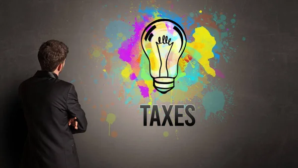 Бизнесмен Рисует Красочную Лампочку Надписью Taxes Текстурированной Бетонной Стене Новая — стоковое фото