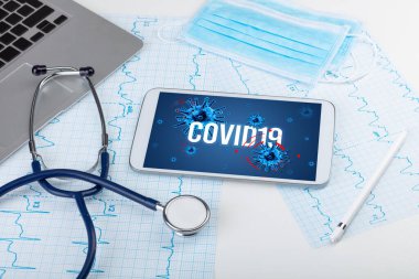 Beyaz yüzeyde COVID19 yazı, salgın konsepti içeren tablet bilgisayar ve doktor araçları