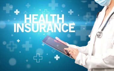 Doktor panoya HeALTH INSURANCE yazısını, ilk yardım kavramını içeren notlar yazar.