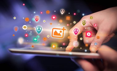 Renkli resim ekleme simgeleri içeren tablet kullanan bir elin yakın plan resmi, sosyal ağ konsepti