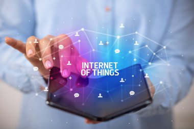 İş adamı elinde, üzerinde yeni teknoloji kavramı ve yazıtların olduğu katlanabilir bir akıllı telefon tutuyor.