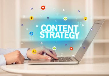 CONTENT STRATEGY yazıtlı, Sosyal medya konseptli dizüstü bilgisayar kullanan serbest çalışan kadın
