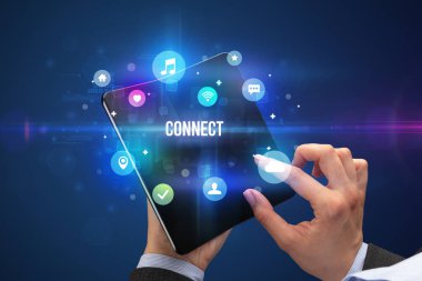 İş adamı, üzerinde CONNECT yazıları ve sosyal medya konsepti olan katlanabilir bir akıllı telefon tutuyor.