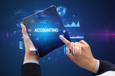 İş adamı elinde katlanabilir bir akıllı telefon ile muhasebe defteri tutuyor. Başarılı bir iş konsepti.