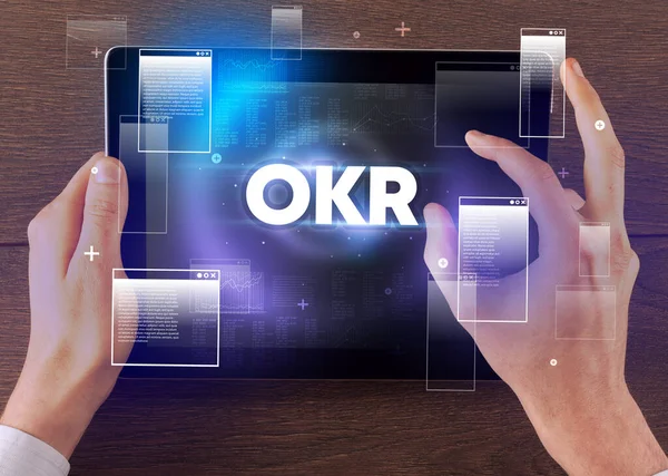 Okrの略語 現代的な技術の概念を持つ手を握っているタブレットのクローズアップ — ストック写真