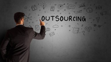 İş adamı, OutTSOURCING yazıtları ve iş stratejisi konseptiyle yaratıcı bir fikir çizimi yapıyor.