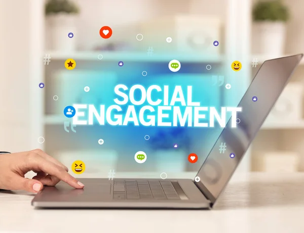 Freelance woman using laptop with SOCIAL ENGAGEMENT inscription, Social media concept