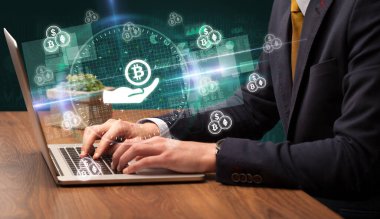 Borsada çalışan iş adamı dizüstü bilgisayardan çıkan bitcoin simgelerini veriyor