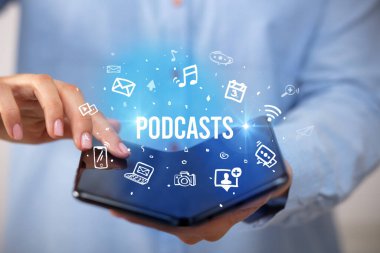 Podcast yazıları ve sosyal medya konsepti olan katlanabilir bir akıllı telefon tutan bir iş adamı