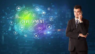 Teknolojiyle ilgili ikonlar ve DEVELOPMENT yazıtları ve modern teknoloji kavramı önünde düşünen iş adamı