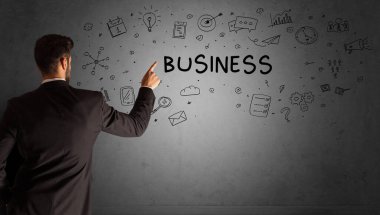 İş adamı, BUSINESS yazıtları ve iş stratejisi konseptiyle yaratıcı bir fikir çizimi yapıyor.