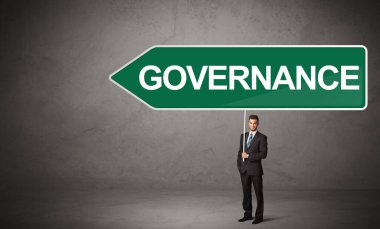 GOVERNANCE yazıtları, yeni iş yönü konsepti ile günlük bekleme yolu tabelasında genç iş adamı