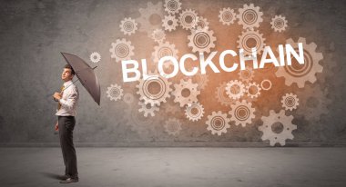 BLOCKCHAIN yazıtlarından şemsiyeyle savunma yapan işadamı, teknoloji kavramı