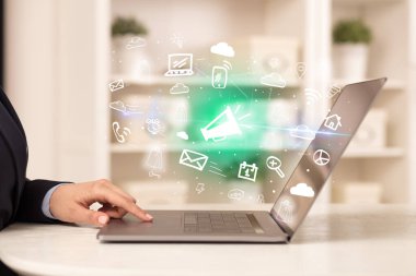 Dizüstü bilgisayarda çalışan iş adamı, içinden megafon simgeleri çıkıyor, iş dünyası kavramı büyüyor.