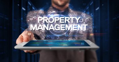 Young business person working on tablet and shows the inscription: PROPERTY MANAGEMENT, business concept