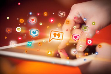 Renkli yazı simgeleri içeren tablet kullanan bir elin yakın plan görüntüsü, sosyal ağ konsepti