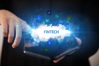 FINTECH yazıtlı, teknoloji konseptli katlanabilir bir akıllı telefon tutan bir iş adamı