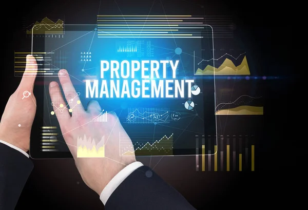 Close-up of hands holding tablet with PROPERTY MANAGEMENT inscription, modern business concept
