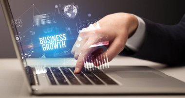İş adamı bilgisayarında Business Growth yazıtı ve yeni iş konseptiyle çalışıyor.