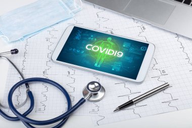 COVID19 yazıtları, koronavirüs kavramına sahip tablet bilgisayar ve doktor araçları