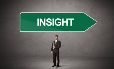 Genç iş adamı, içinde INSIGHT yazıtları ve yeni iş yönü kavramı olan günlük bekleme yolu tabelasında.