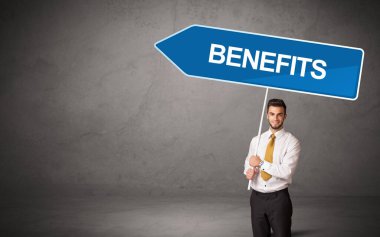 Genç iş adamı, gelişigüzel yol tabelasında BENEFITS yazısıyla, yeni iş yönü kavramı